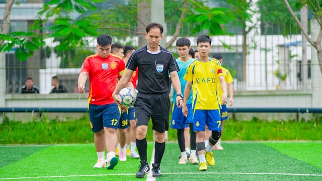 Soccer players and referee entering a field in Hanoi, Vietnam, showcasing teamwork and sportsmanship.