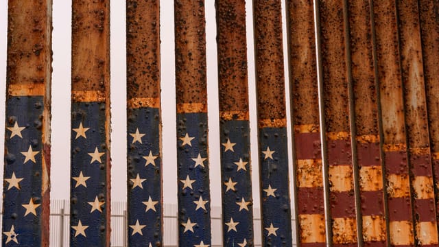 Close-up of a rusty iron fence painted with stars and stripes at the American-Mexican border in Tijuana.