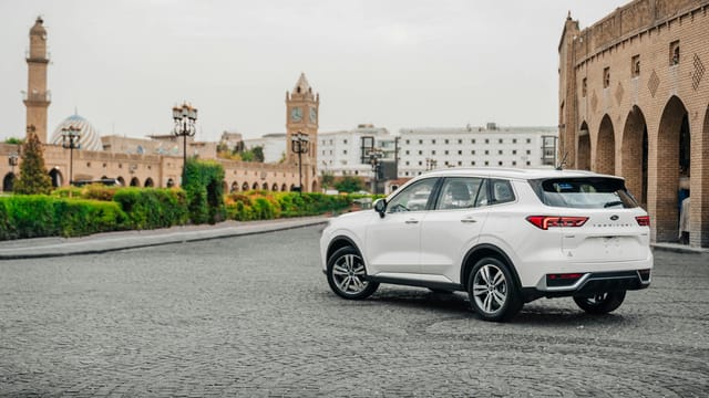 White SUV parked in a historic square in Erbil, Iraq with traditional architecture.