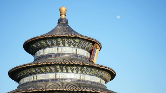 Iconic Temple of Heaven with a clear blue sky and moon in Beijing, China.