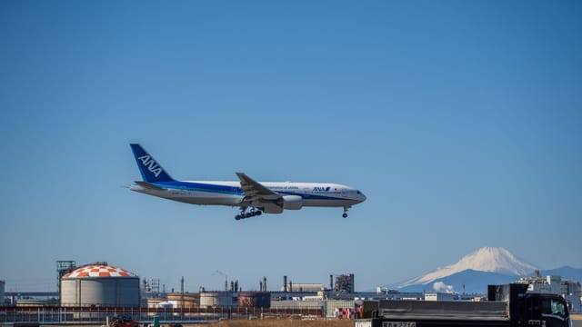 Airplane approaching runway with Mount Fuji in the background, showcasing travel and aviation.