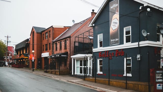 Aged and contemporary building facades with signboard near empty asphalt roadway under sky in town