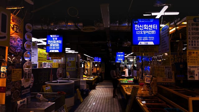 Explore the bustling atmosphere of a Korean fish market in Gangneung, filled with fresh seafood offerings.