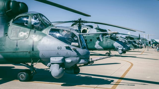 Line of military helicopters on an airfield under clear blue skies in Brasília, Brazil.