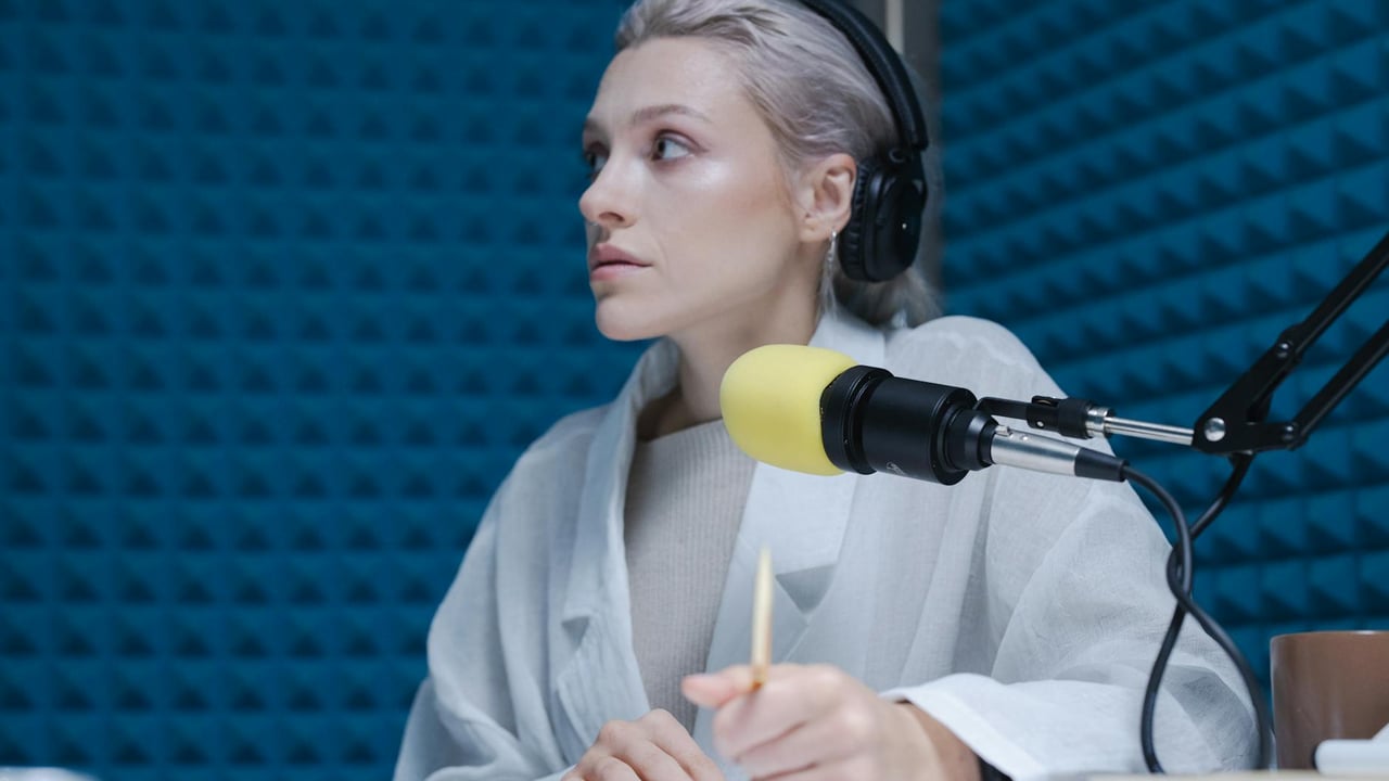 Confident woman wearing headphones hosting a podcast in a soundproof studio.