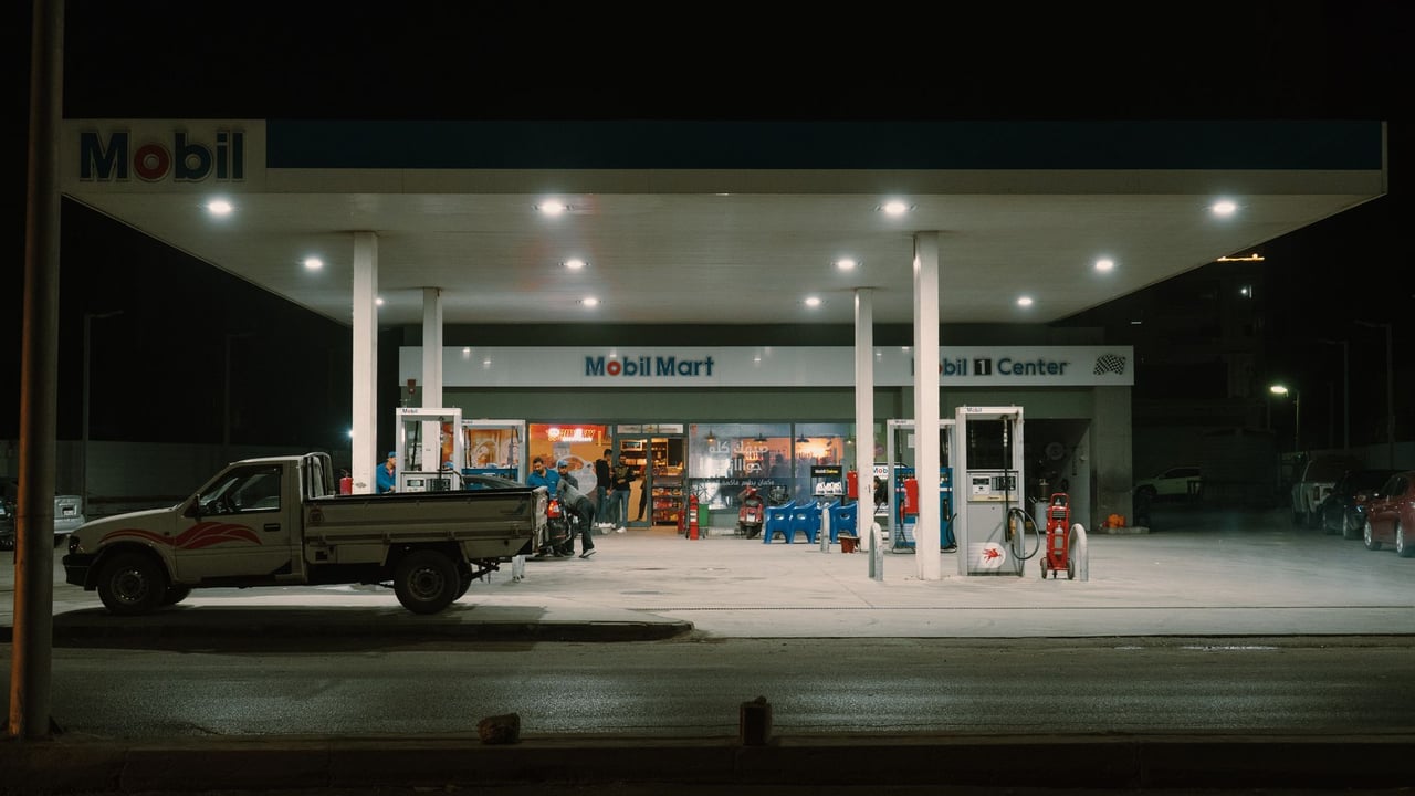 A Mobil gas station with vehicles and people under bright lights at night.