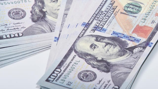 A detailed close-up of stacked US 100 dollar banknotes representing wealth and finance.