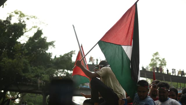 Pro-Palestine rally in Dhaka, Bangladesh with demonstrators waving flags in solidarity.