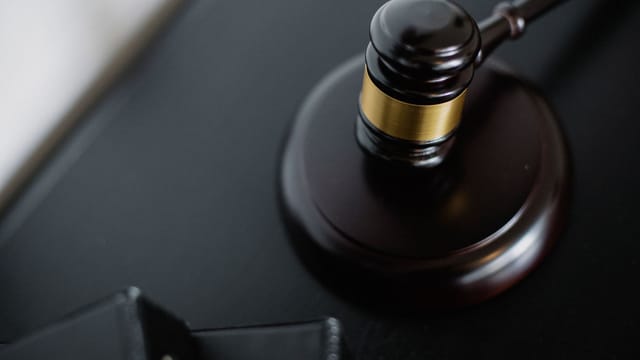 From above of wooden gavel on round surface near folders on table in courtroom