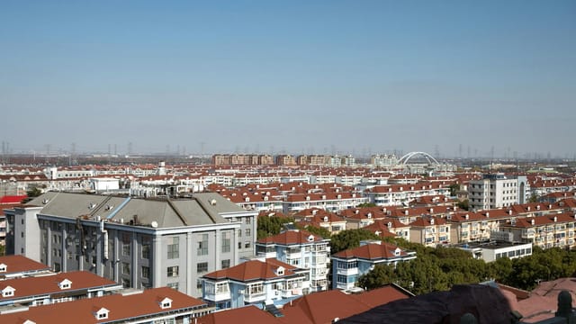A scenic aerial view of Shanghai's red-roofed residential district under a clear blue sky.