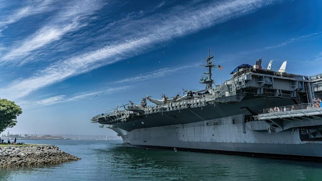 USS Midway Museum ship docked in San Diego harbor on a clear day, showcasing naval history.