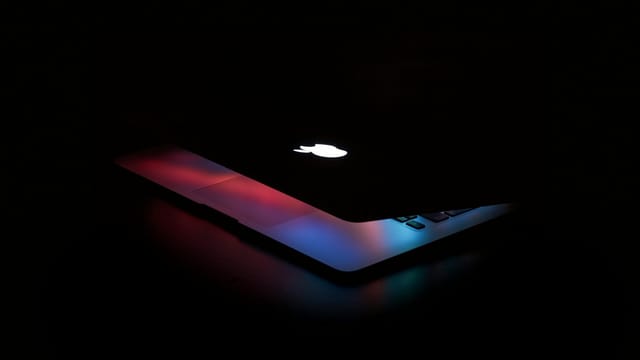 Captivating close-up of a partially open laptop with colorful lighting against a dark background.