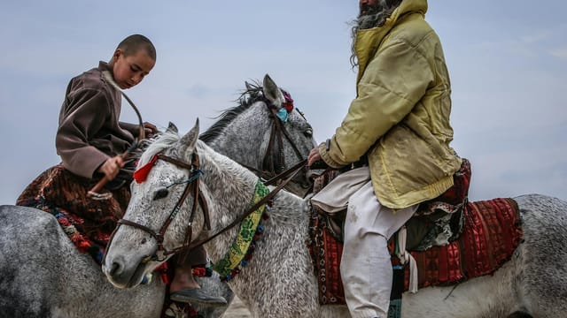 Two individuals on horseback engage in cultural riding in Balkh, Afghanistan.