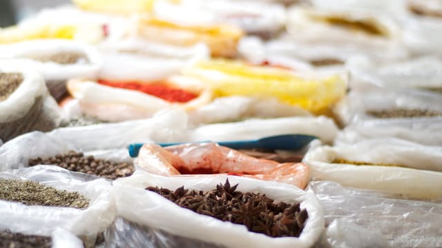 Vibrant selection of spices in plastic bags on display at a bustling market.