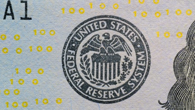 Detailed view of the US Federal Reserve System seal on currency with yellow digital numbers.