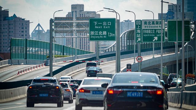 Cars on an elevated highway navigating through Shanghai's urban landscape.