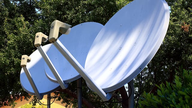 Satellite dishes in nature setting, emphasizing technology blend with environment.