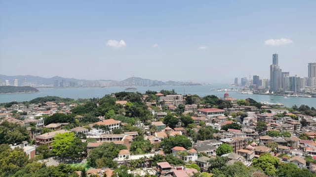 Scenic aerial view of Xiamen's coastal cityscape with clear skies and urban architecture.