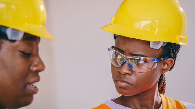 Close-up of African American construction workers wearing safety gear, including helmets and vests.