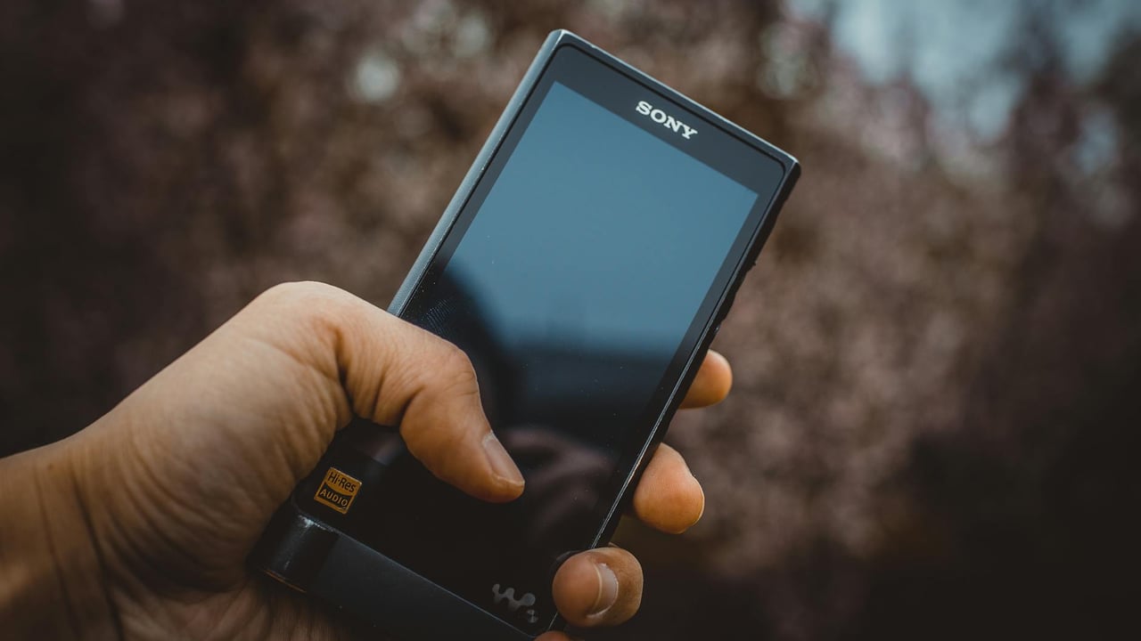Close-up of a hand holding a portable audio device with high-res audio support.