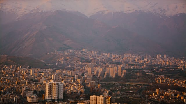 Majestic view of Tehran cityscape and the Alborz mountains during twilight, showcasing urban and natural beauty.