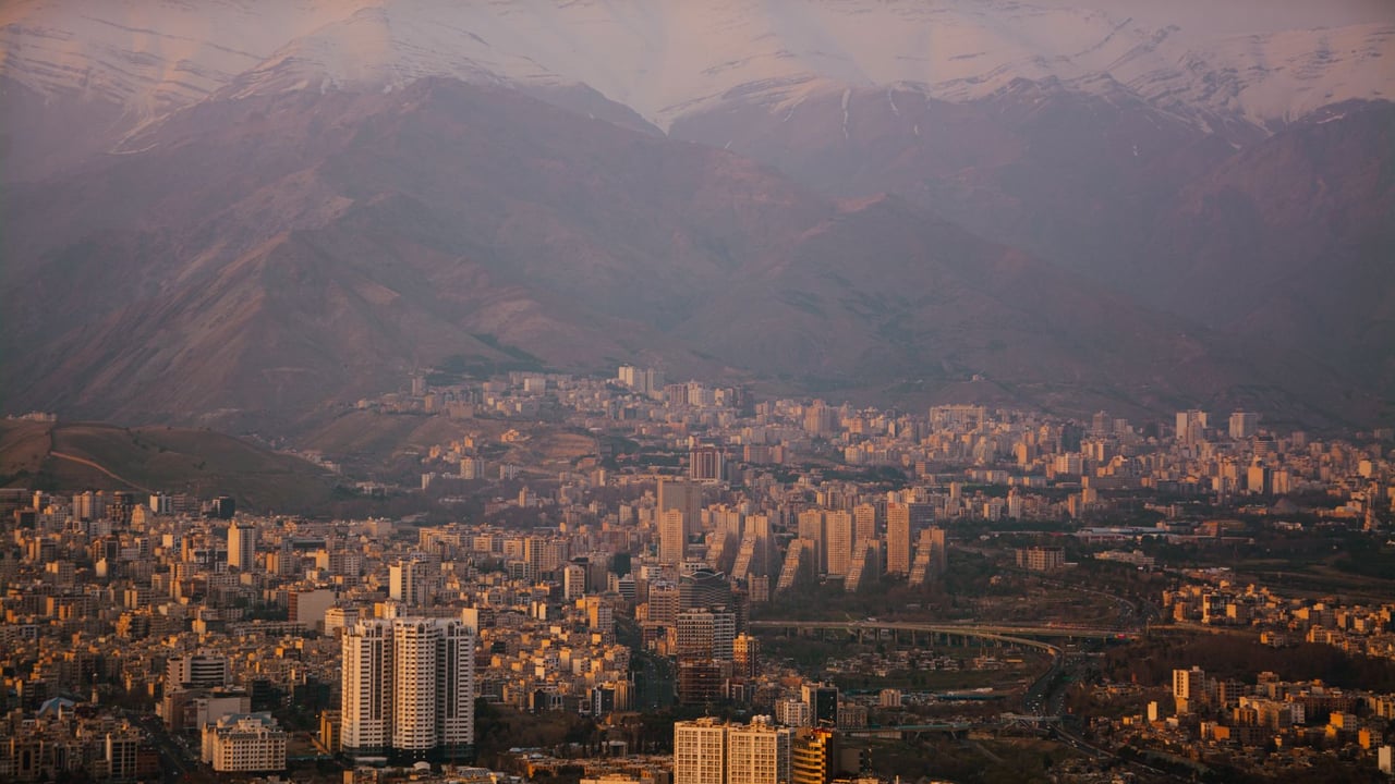Majestic view of Tehran cityscape and the Alborz mountains during twilight, showcasing urban and natural beauty.