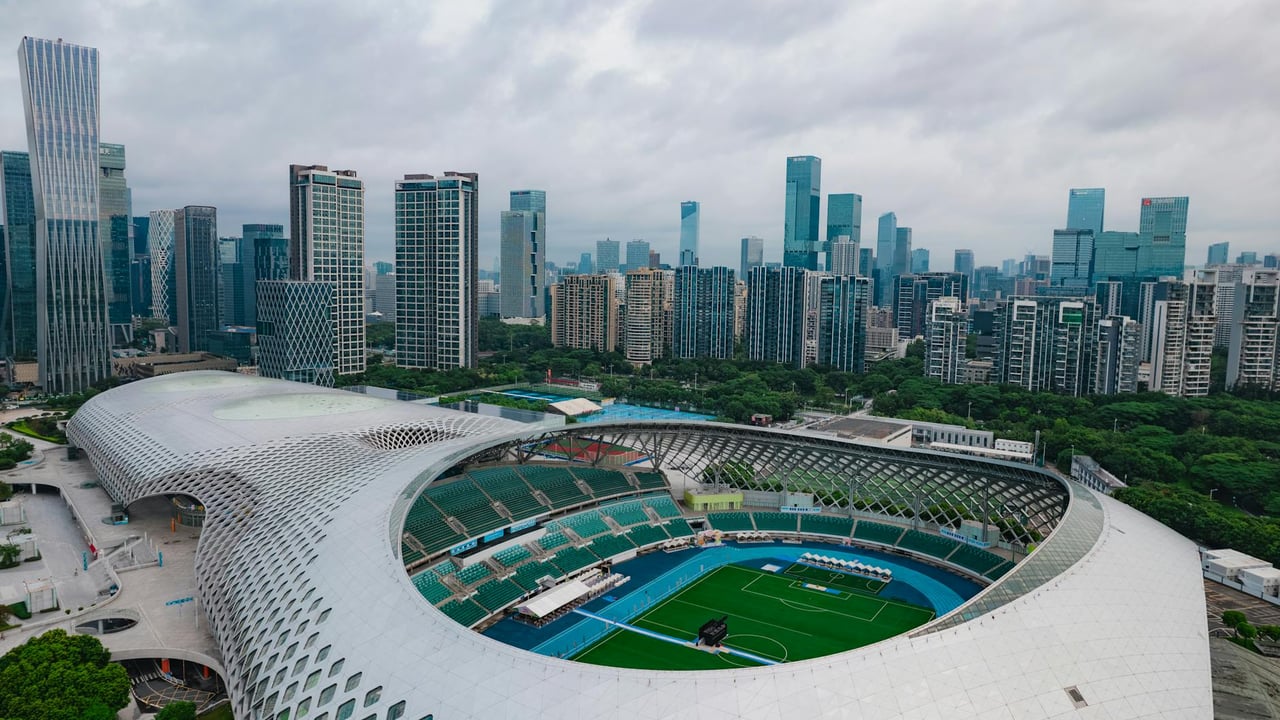 Stunning aerial shot of Shenzhen's modern stadium surrounded by skyscrapers, showcasing urban architecture and cityscape.