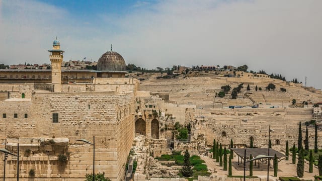 View of ancient Islamic architecture in Jerusalem with stone walls and domes under a clear sky.