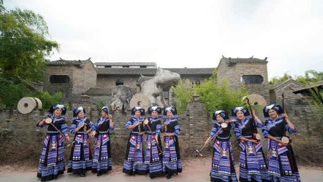 Zhuang women in vibrant ethnic costumes performing traditional music in Guangxi.