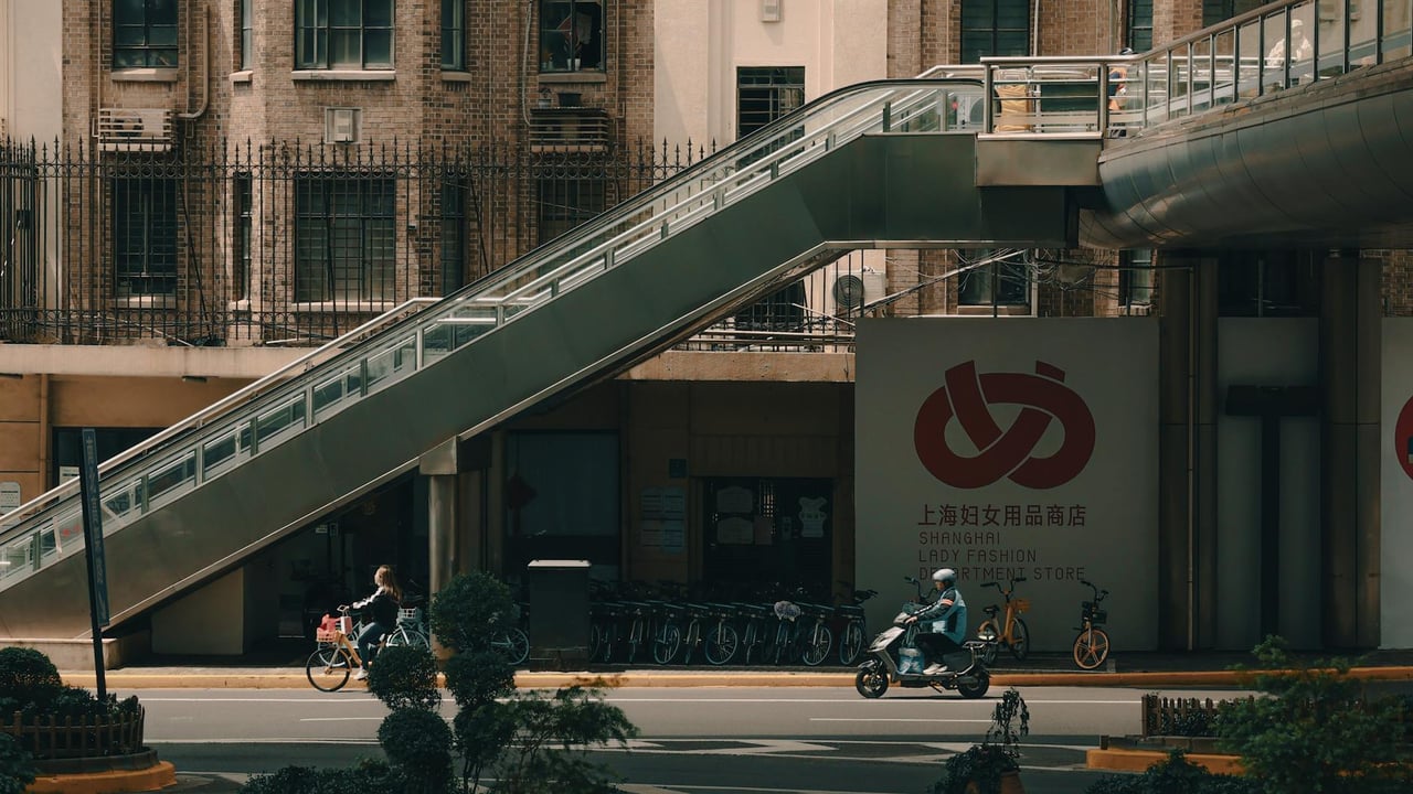 Street view in Shanghai showing an escalator, bicycles, and people in motion.