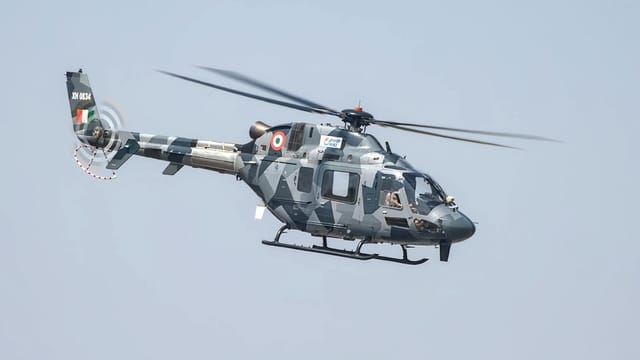 A camouflaged Indian Air Force helicopter in flight at Bengaluru air show.