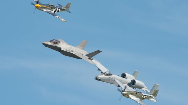 Three different military aircraft flying in formation against a clear blue sky.