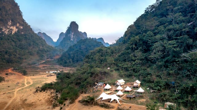 Scenic aerial view of tents nestled in a mountain valley lush with greenery.
