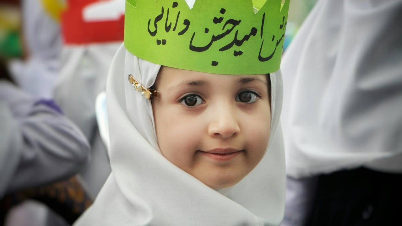 Portrait of a young girl in traditional white attire and green crown during a cultural event in Tehran.