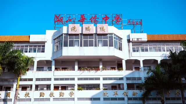 A large urban school building with palm trees and bright signage under a clear blue sky.