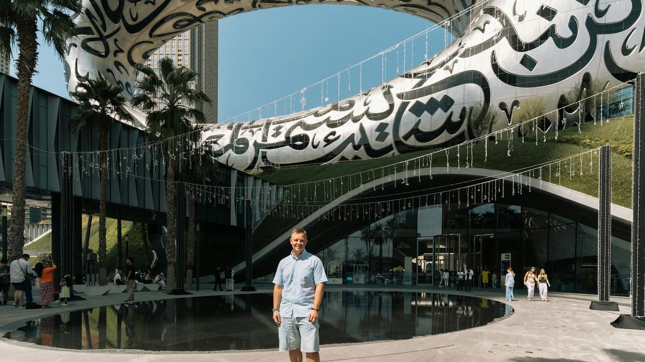 Man stands in front of Dubai's Museum of the Future, showcasing modern architecture.