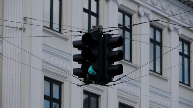 Close-up of a traffic light with a green signal in front of a historic building facade.