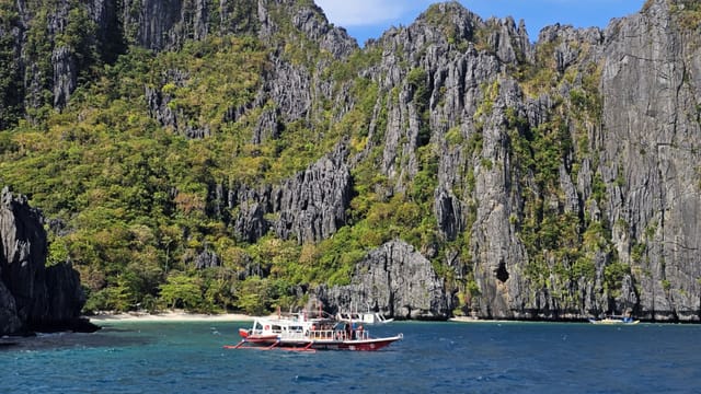 Enjoy a breathtaking view of boats by the limestone cliffs of El Nido, Philippines.
