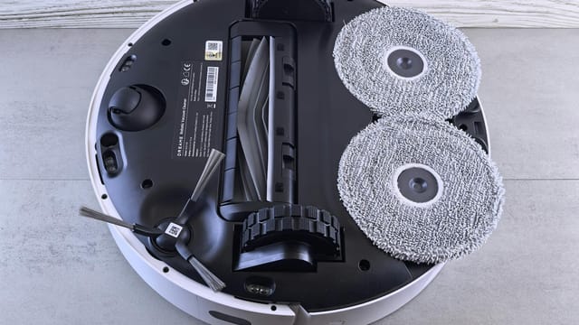 Detailed view of a robotic vacuum cleaner's underside showing brushes and wheels.