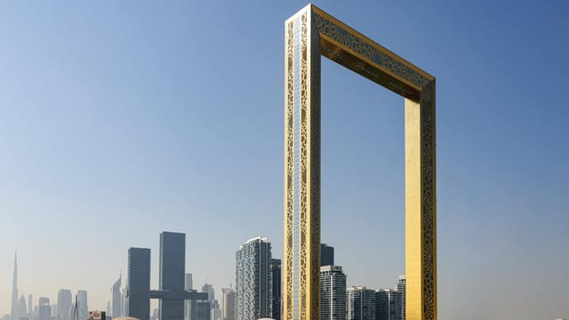 The iconic Dubai Frame with city skyscrapers in the background under a clear sky.