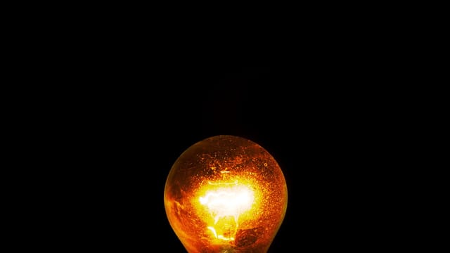 Close-up of a glowing light bulb against a dark background, symbolizing energy and innovation.