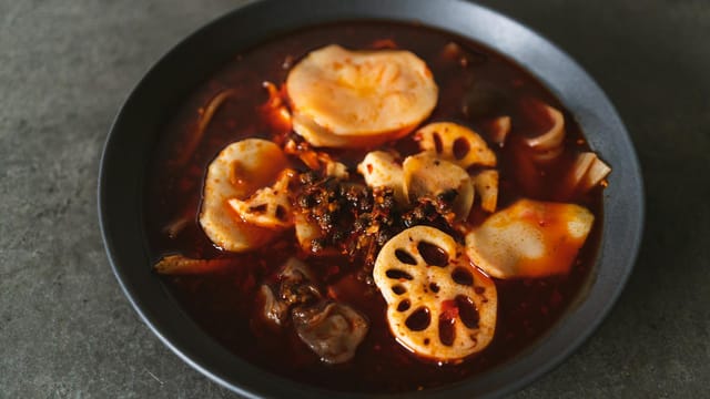 A delicious bowl of Sichuan hotpot featuring lotus roots and potatoes in spicy broth.