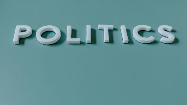 Close-up image of the word 'Politics' against a teal green background, highlighting political themes.