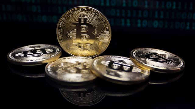 Close-up of gold Bitcoin coins against a digital binary code background, symbolizing modern finance.