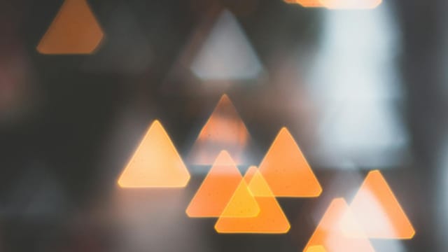 Illuminated abstract triangle bokeh lights creating a soft, defocused pattern.