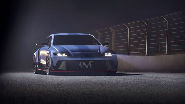 A modern blue sports car parked on an illuminated track at night, showcasing its sleek design.