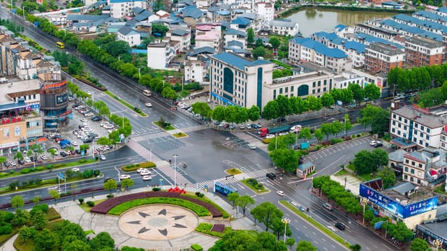 Aerial view of a modern cityscape in China with roads, buildings, and greenery.