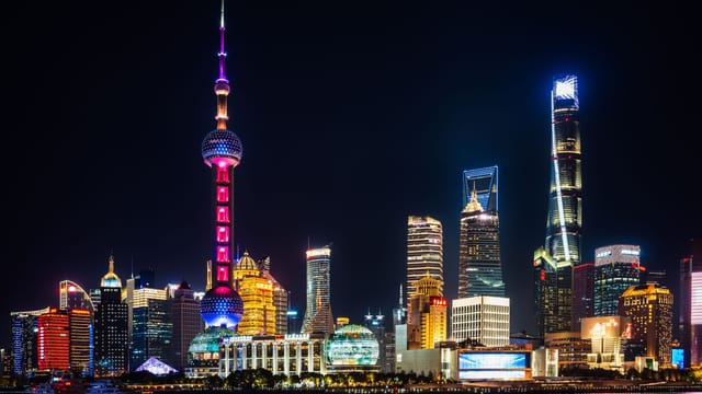 Vibrant night view of Shanghai's illuminated skyline featuring the iconic Oriental Pearl Tower.
