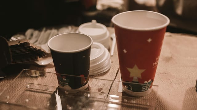 Disposable holiday-themed coffee cups on a table, perfect for seasonal drinks.