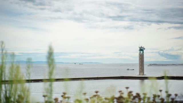 Concrete lighthouse overlooking the sea with cloudy skies in Osaka Bay, Japan.